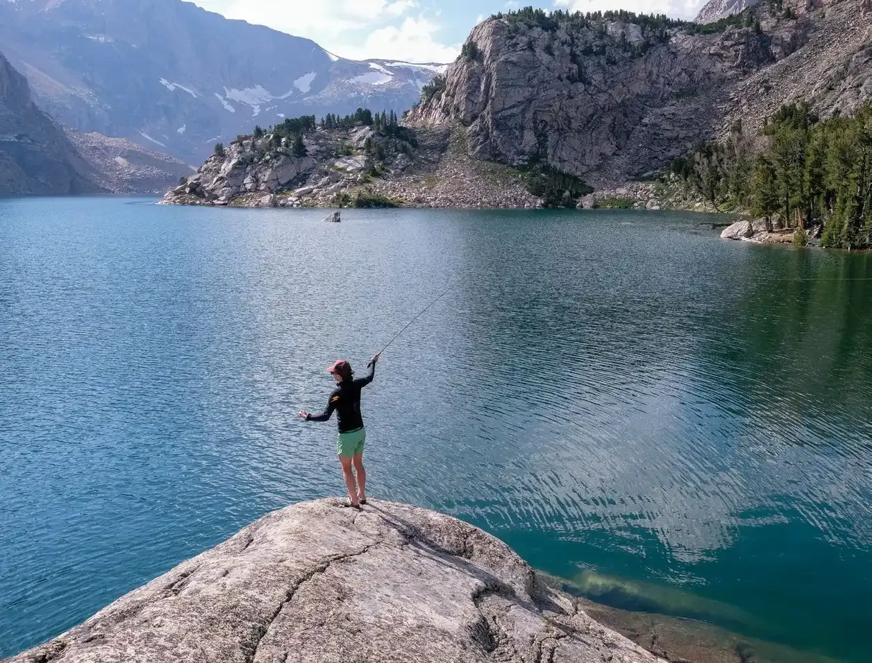 The Shifting Wild of Adventuring with Kids 3 Caroline casting a dry fly into the clear water of Glacier Lake