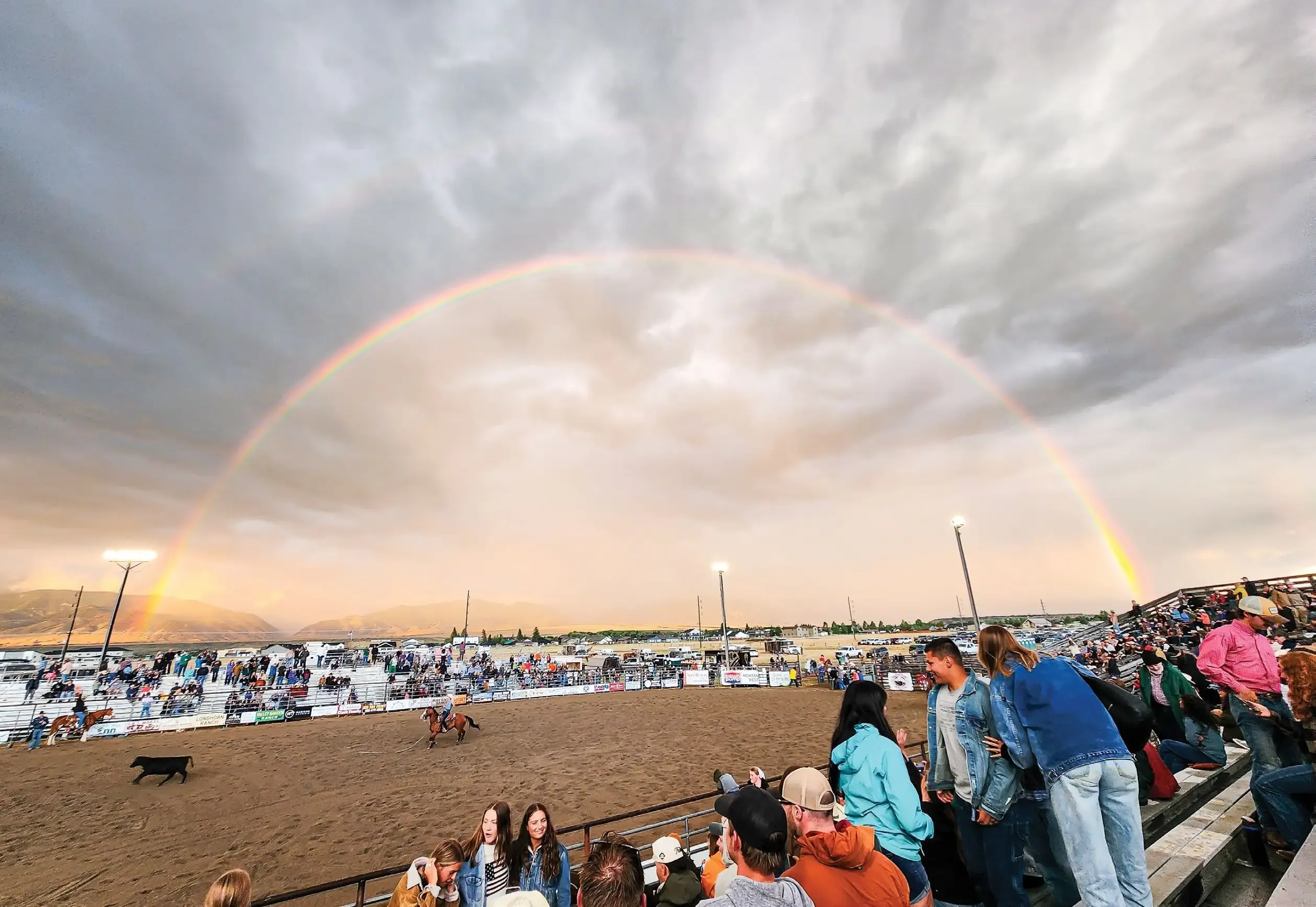 Boot-Top Deep in Montana Rodeo 3 Spectators at the Ennis Rodeo watch a rainbow arch above the grounds