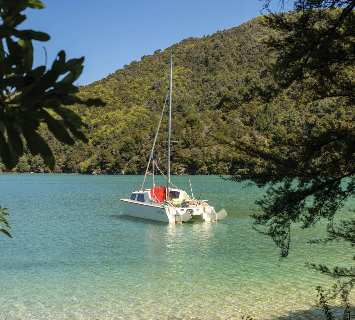 A lone sailboat in turquoise Torrent Bay along the Abel Tasman Track
